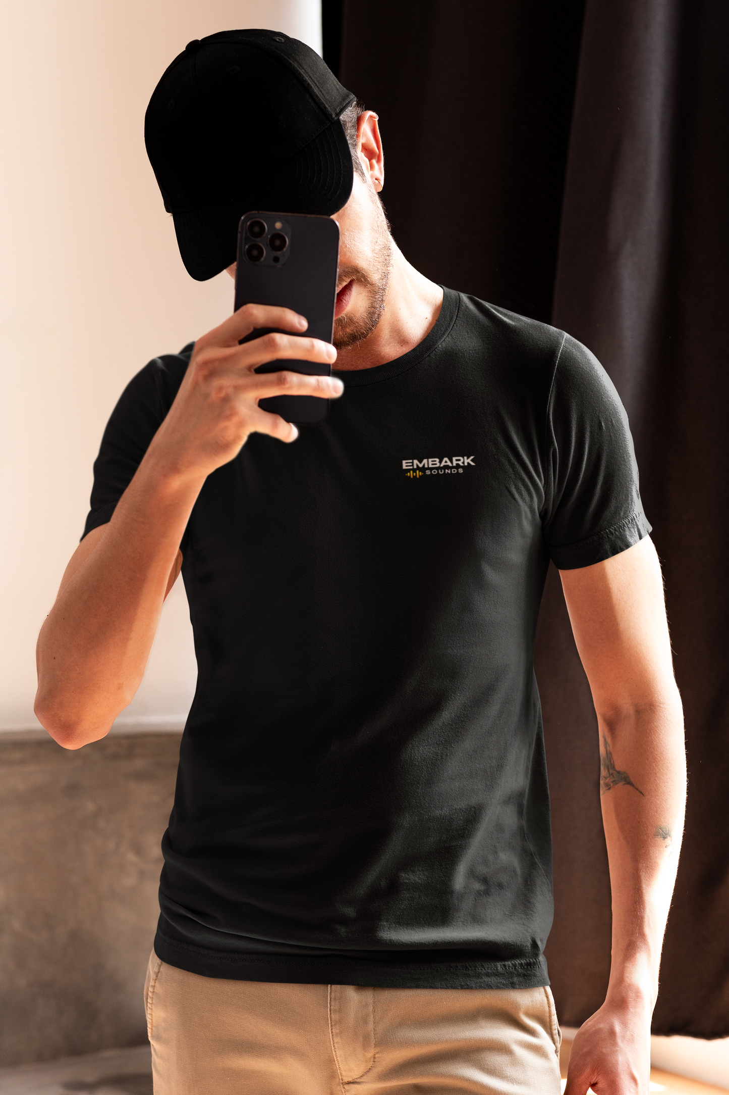 Man wearing a black t-shirt with text, taking a mirror selfie.